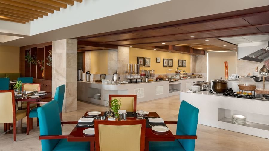 Modern restaurant dining area with turquoise chairs and elegant decor at Ramada by Wyndham Ghaziabad Vasundhara