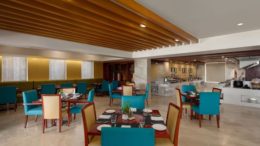 Spacious dining hall with blue chairs and modern ceiling design at Ramada by Wyndham Ghaziabad Vasundhara