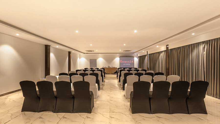 Spacious meeting room arranged with rows of chairs for a presentation.