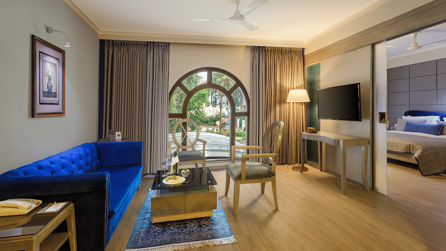 A suite with a queen size bed, a couch, a coffee table, and an arched glass doorway at Ramada by Wyndham Mussoorie Mall Road.