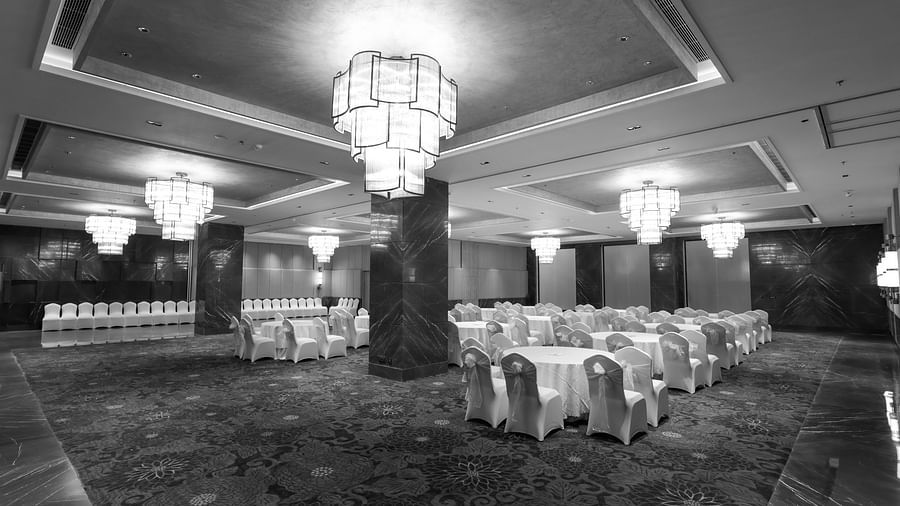 Spacious banquet hall with elegant chandeliers and round table seating at Ramada by Wyndham Sonipat Murthal
