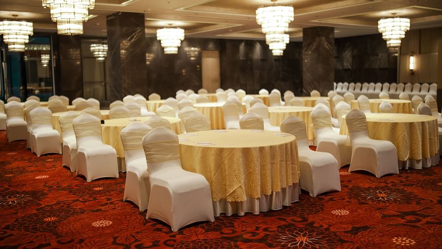 Banquet setup with round tables and white chair covers on a vibrant red carpet at Ramada by Wyndham Sonipat Murthal