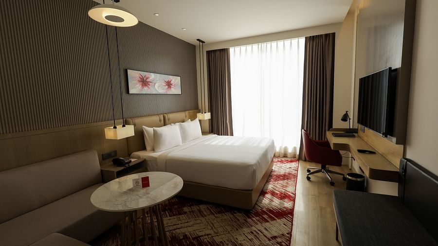 Room with seating area and a bed, offering ample natural light at Ramada by Wyndham Sonipat Murthal