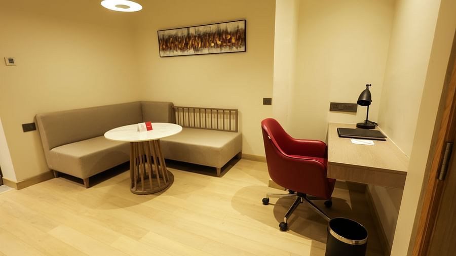 Compact work area with desk, red chair, and casual round table seating at Ramada by Wyndham Sonipat Murthal