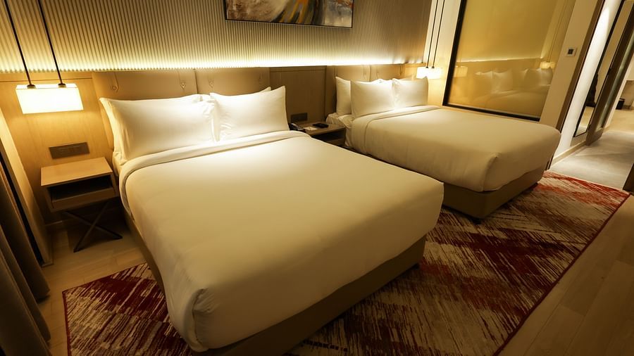 Warmly lit bedroom with wooden furnishings and red-patterned carpet at Ramada by Wyndham Sonipat Murthal