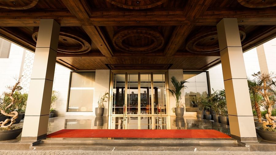 Main glass door entrance with red carpet and potted plants at Ramada by Wyndham Sonipat Murthal