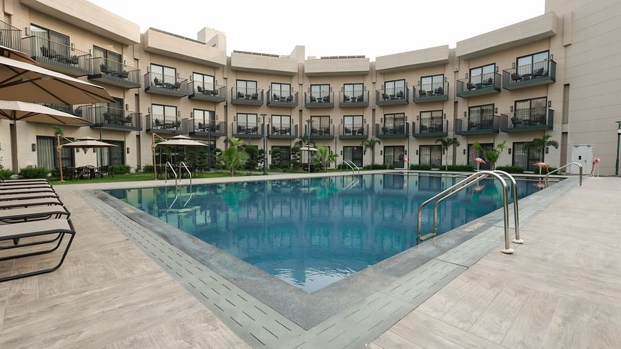 Large outdoor swimming pool surrounded by balconies at Ramada by Wyndham Sonipat Murthal