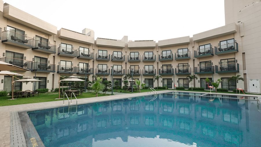 Poolside view of the hotel's courtyard and room balconies at Ramada by Wyndham Sonipat Murthal