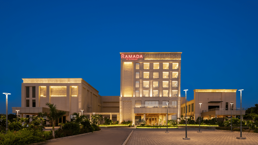 Front view of Ramada by Wyndham Sonipat Murthal illuminated against the evening sky, highlighting its modern design.