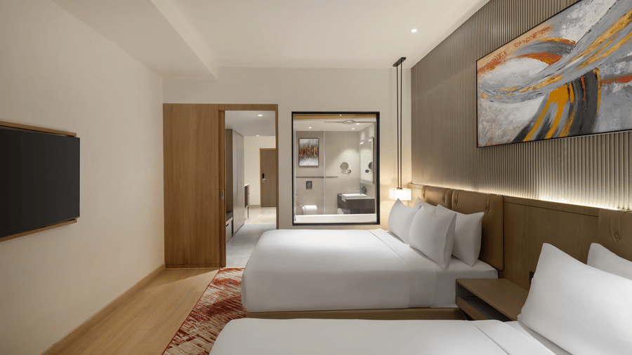 Well-appointed hotel room at Ramada by Wyndham Sonipat Murthal, with a king-size bed, flat-screen television, wooden wardrobe, and a patterned area rug on a wooden floor.