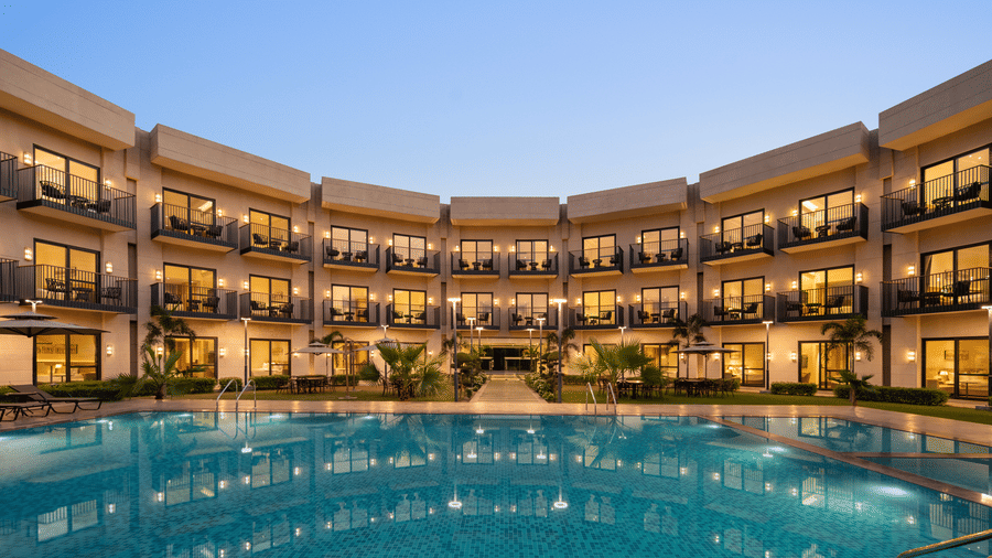 Large outdoor swimming pool with surrounding accommodations and ambient evening lighting at Ramada by Wyndham Sonipat Murthal.