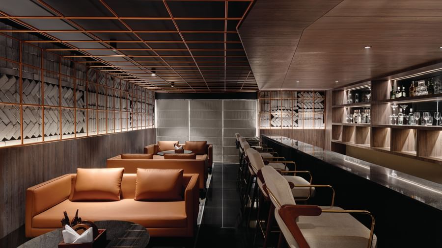 Bar at Ramada Encore by Wyndham, Bhiwadi with rows of aligned orange couches.