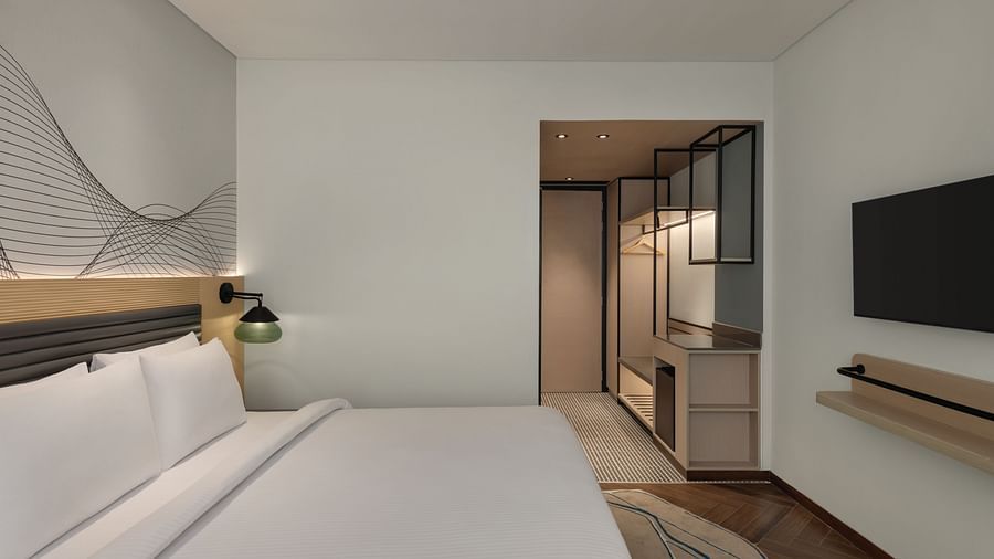 Ramada Encore by Wyndham, Bhiwadi | Hotel bedroom with a view into the bathroom, white bed, and modern decor.