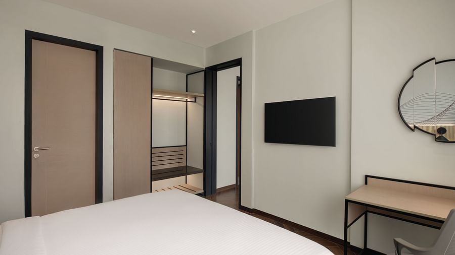 Ramada Encore by Wyndham, Bhiwadi | Hotel room with white bed, desk, mirror, and a view into the bathroom