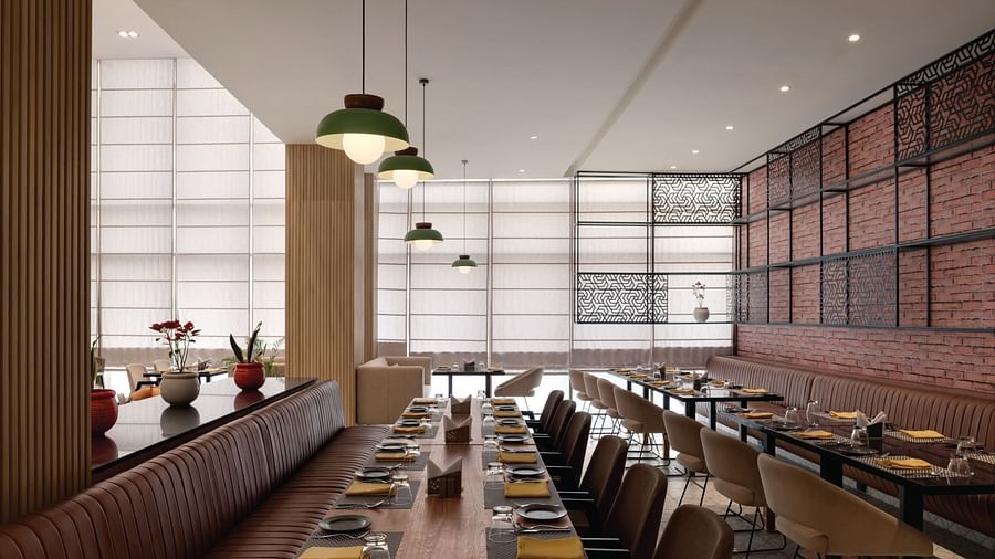 Ramada Encore by Wyndham, Bhiwadi | Restaurant with long tables, booth seating, and pendant lighting.