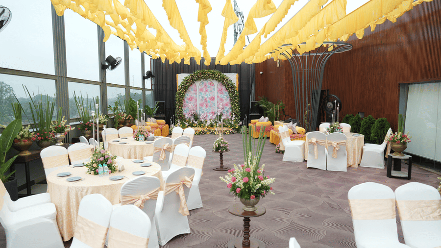 Bright wedding seating area with white chairs, floral centrepieces, and yellow draped decor. | Best place for wedding in Chandigarh
