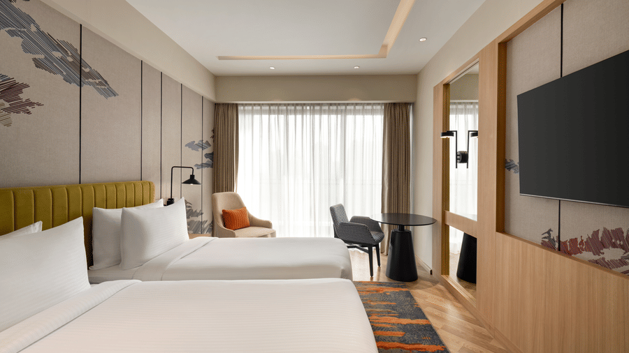 Contemporary hotel bedroom at Ramada Encore by Wyndham Gurugram Dwarka Expressway, featuring a comfortable king-size bed, television and stylish interiors.
