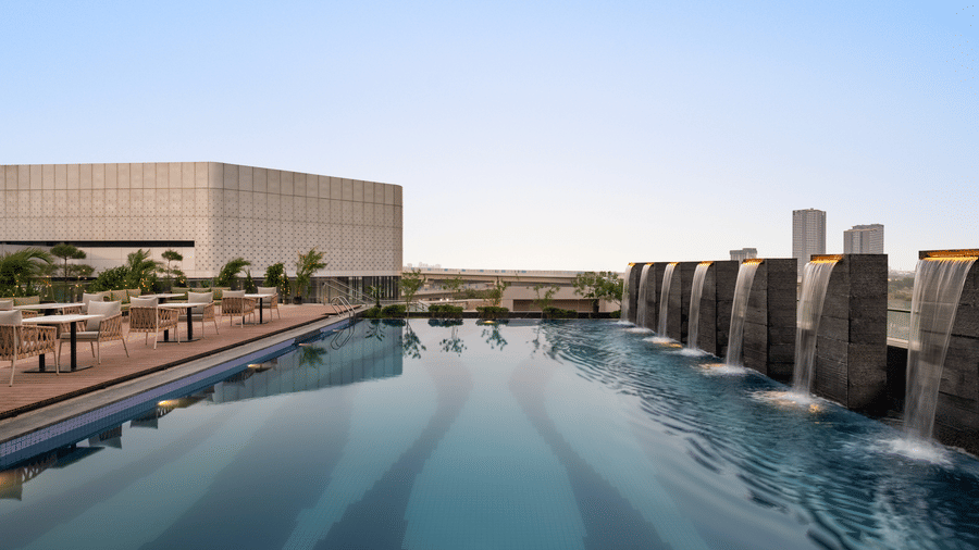 Rooftop infinity-style swimming pool at Ramada Encore by Wyndham Gurugram Dwarka Expressway, surrounded by a spacious deck and outdoor seating.