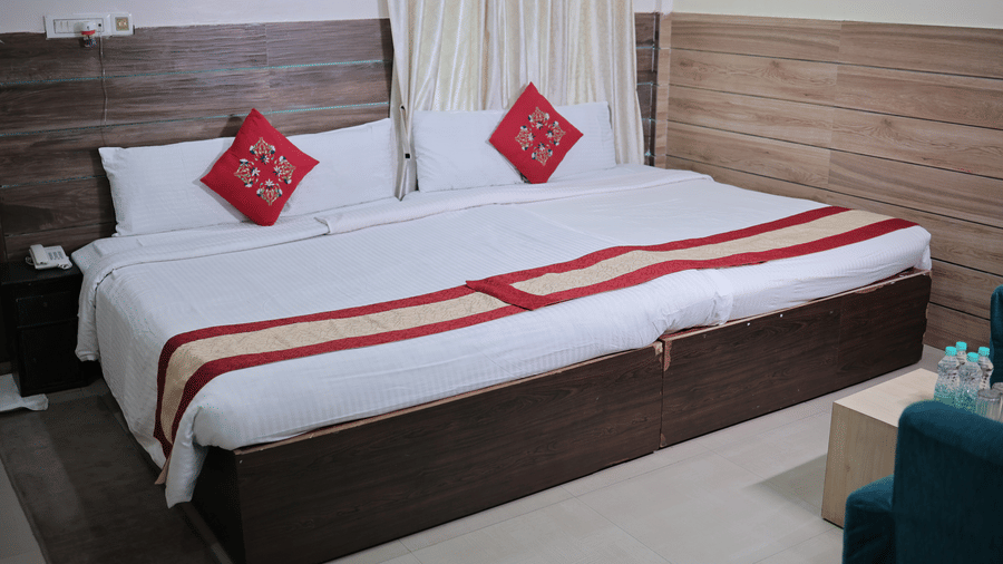 A neat resort hotel room featuring a double bed with white sheets and red accent pillows.