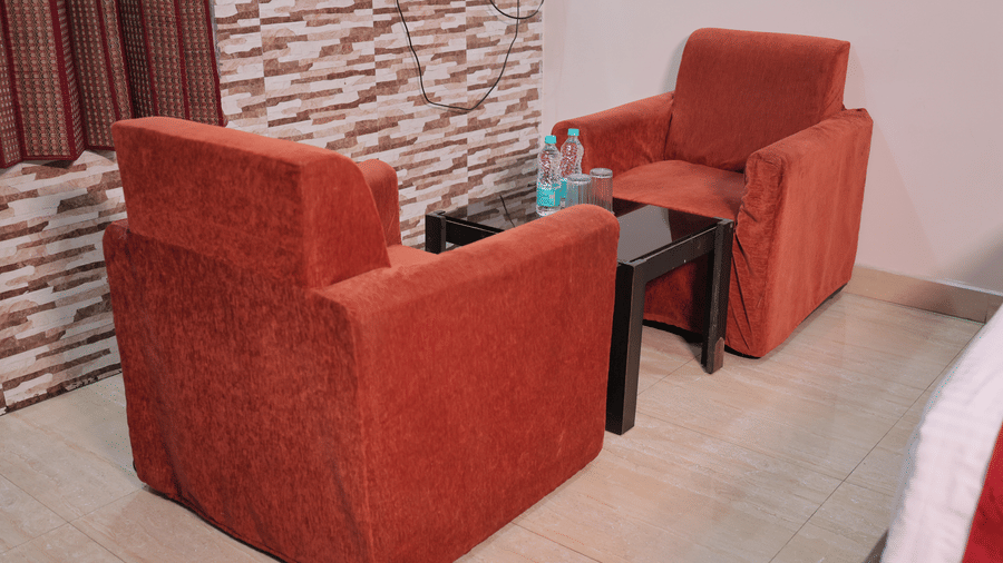 A cosy seating area inside a hotel lounge featuring two plush red armchairs and a small coffee table.