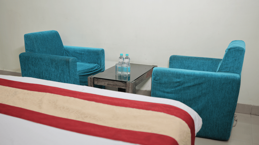 A comfortable seating area in a hotel room featuring two bright blue plush armchairs and a small coffee table.