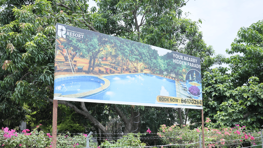 A large outdoor billboard displaying an image of a blue swimming pool, set amongst green foliage.