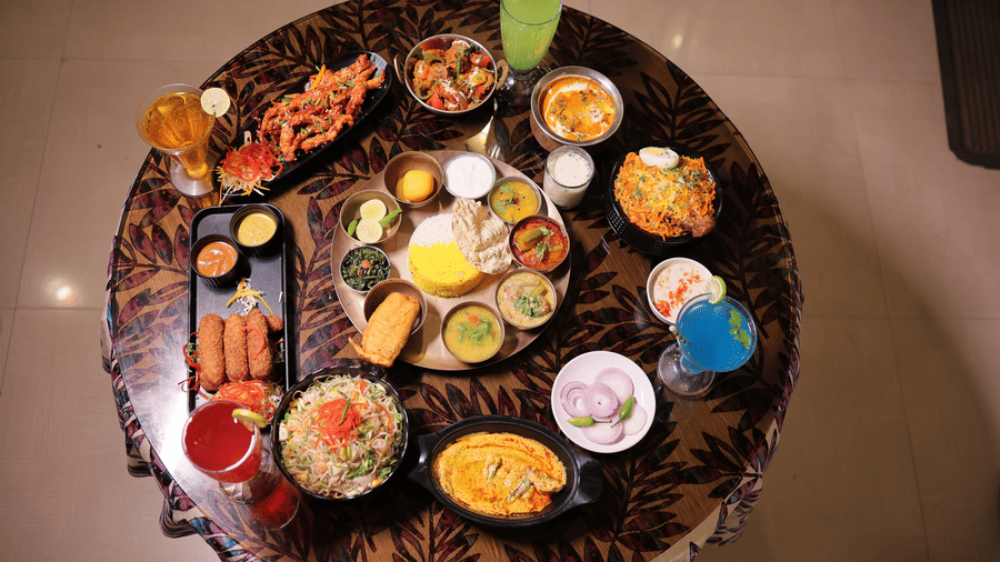 A top-down view of a round table filled with a traditional Indian thali platter and various side dishes.