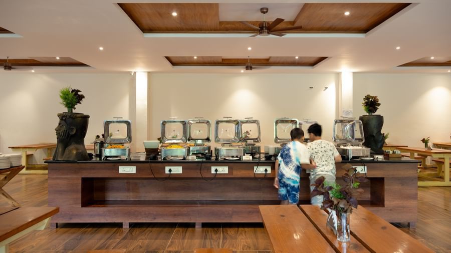 A well-lit indoor dining area features a buffet setup with multiple food warmers and a few people present | Lake View Restaurant