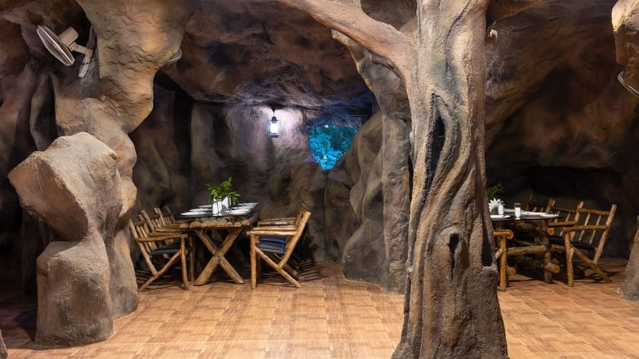 A cave-themed restaurant shows more seating arrangements with wooden tables and chairs amidst sculpted rock walls | Cave Restaurant