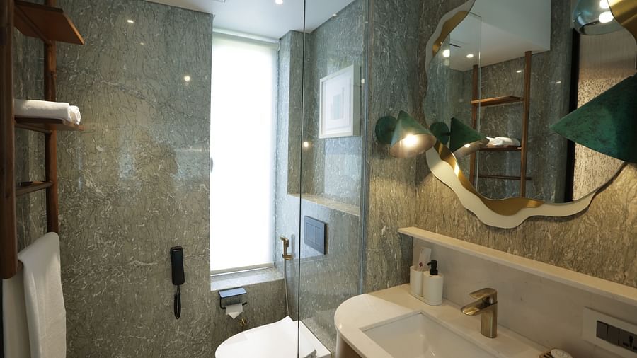 Elegant bathroom interior at Regency Hotel, Mumbai showcasing marble walls, modern fixtures, artistic lighting and premium toiletries for guest comfort.