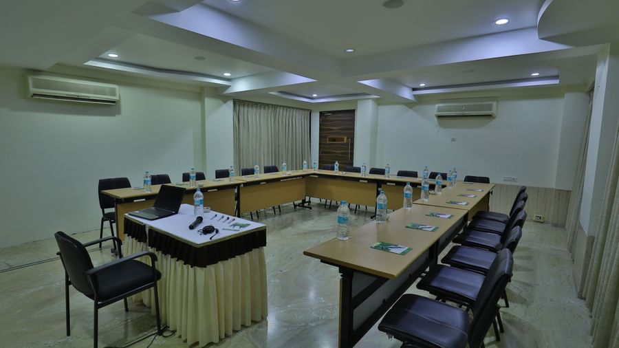 A formal meeting room with a large U-shaped table, office chairs, and a podium at the front - Retreat Heritage, Lonavala