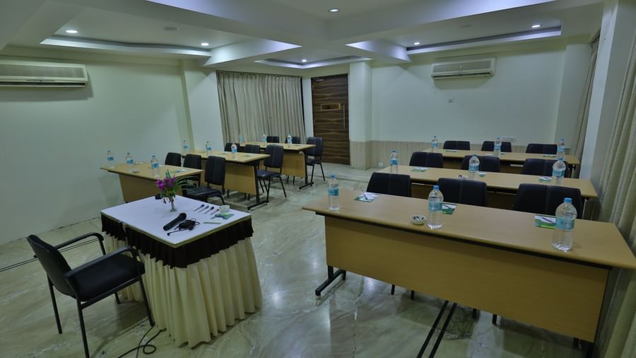 A conference room featuring multiple tables arranged individually, chairs, and a podium at the front - Retreat Heritage, Lonavala