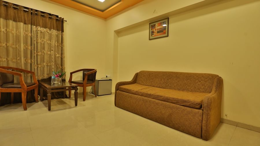 A suite's living room area, furnished with a long sofa, chairs, and a coffee table - Retreat Heritage, Lonavala
