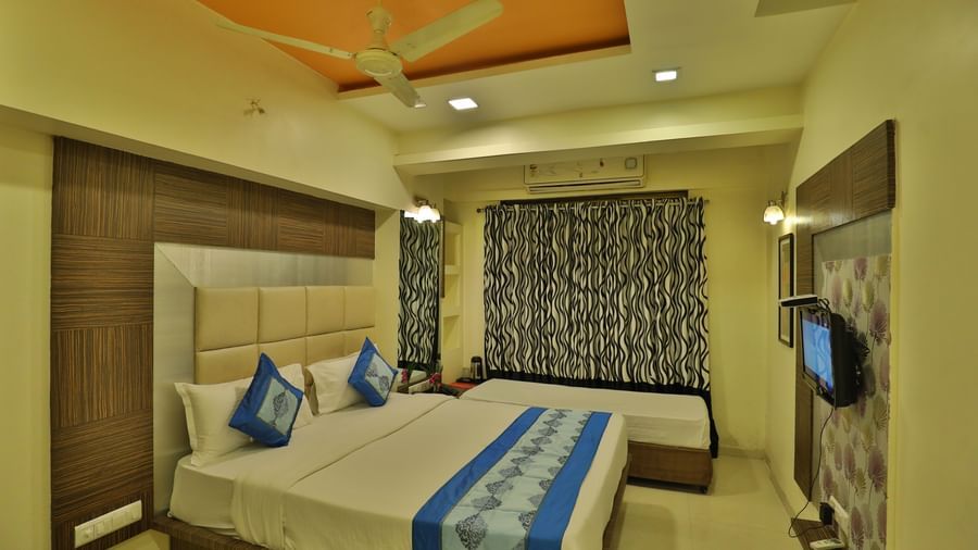 A cosy hotel room with a large bed, side tables, a television, and ample natural light - Retreat Heritage, Lonavala