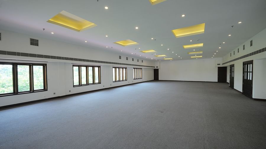 an image of an empty Banquet hall with windows on the side - Rhythm Kumarakom
