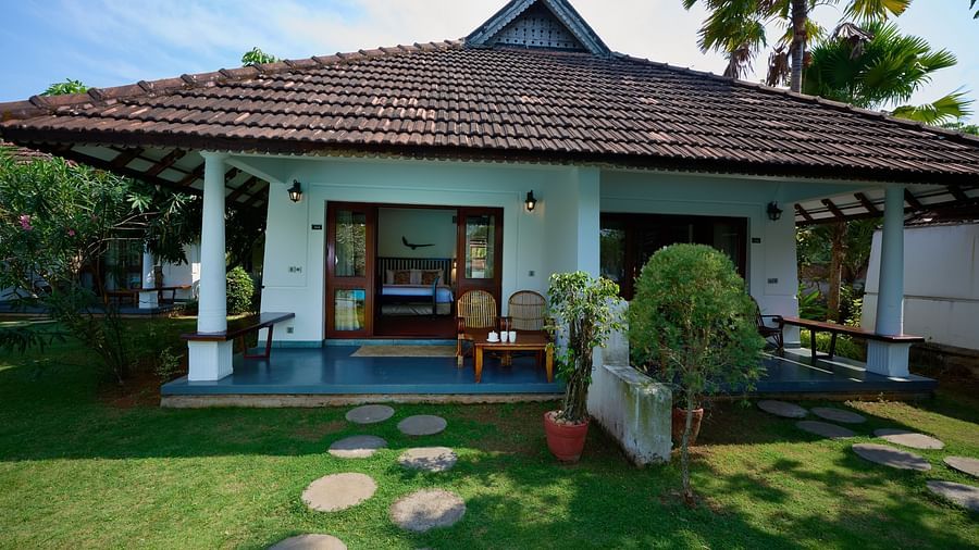 An image of a cottage surrounded by lush green lawn - Rhythm Kumarakom