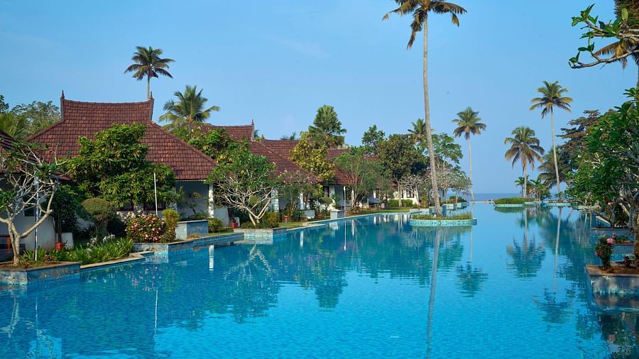 an image of close up shot of a swimming pool with rooms and trees in view - Rhythm Kumarakom