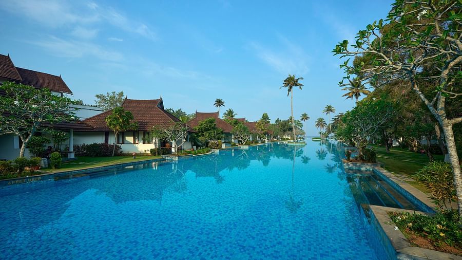 an image of a swimming pool with rooms and trees in view - Rhythm Kumarakom