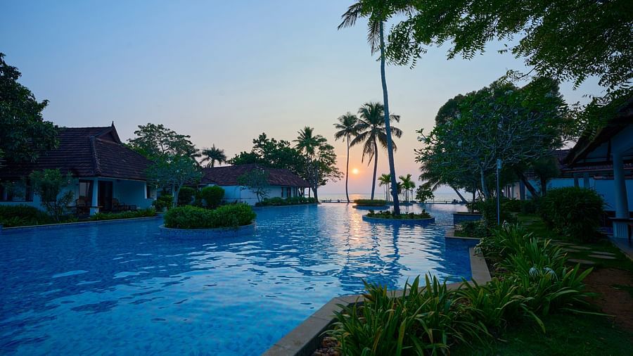 an image of a swimming pool with a sunset background - Rhythm Kumarakom