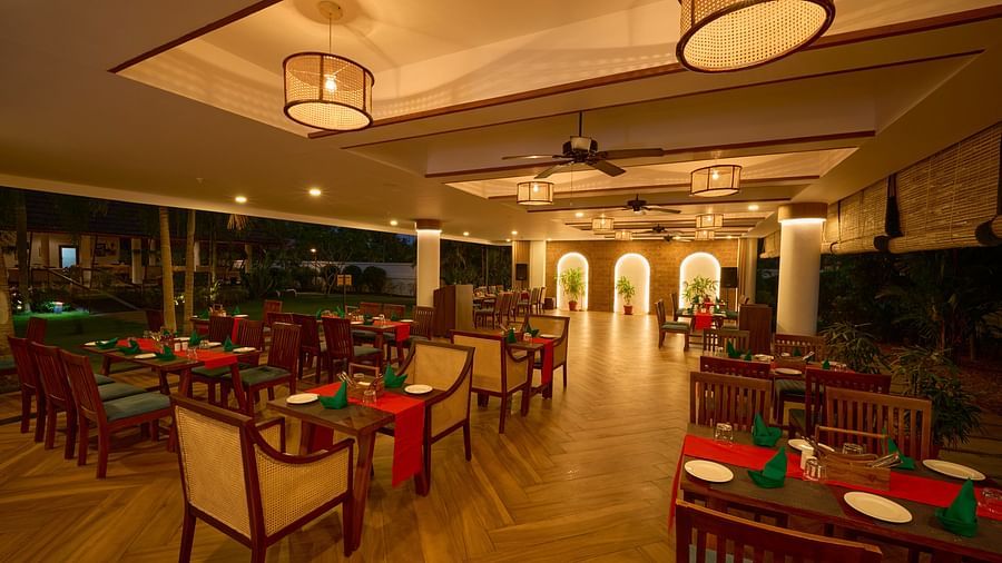 an overview of the seating arrangements inside a restaurant with illuminating yellow lights at Rhythm Kumarakom.