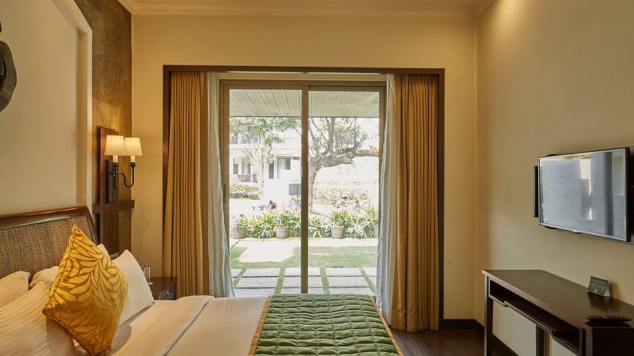 an image of a bedroom with a glass patio door with outdoor view - Rhythm Lonavala