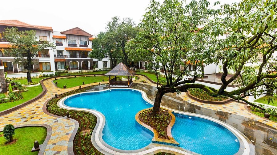 Swimming pool with a tree in the centre of the pool and the resort in the background - Rhythm Lonavala.