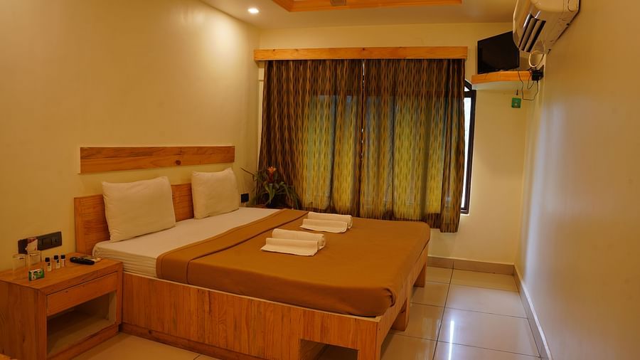 A side view of the room featuring a spacious bed, a bedside table, and a window covered with curtains at Riverside Inn.
