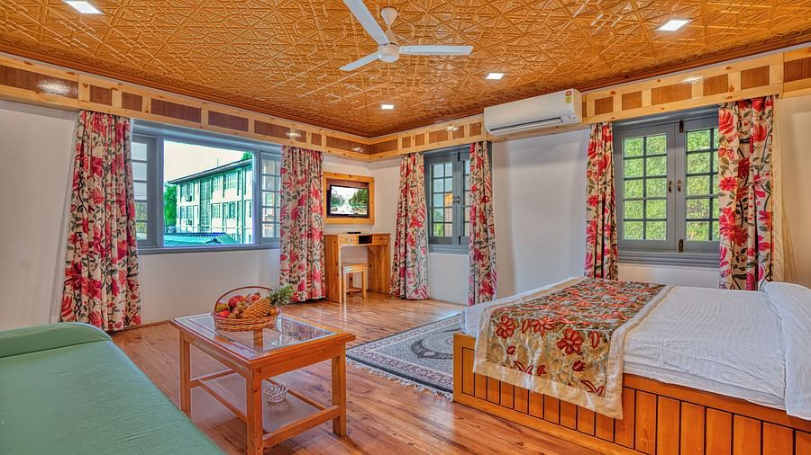 Elegant guest room with wooden accents and floral curtains at Royal Comfort Regency, perfect for a peaceful stay.