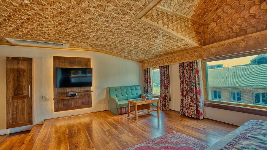 Spacious room at Royal Comfort Regency with wooden flooring, carved ceiling and bright windows for a restful, scenic stay.