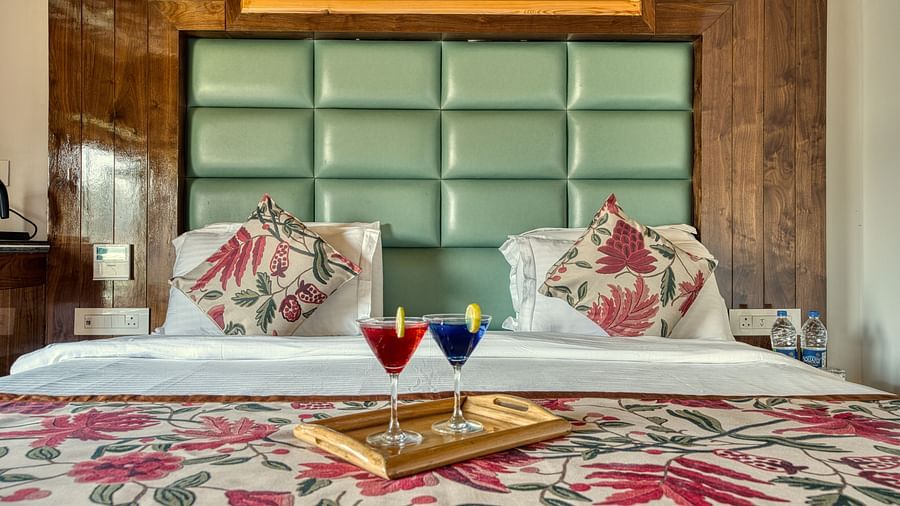 King size bed with floral linen and twin welcome drinks at Royal Comfort Regency, crafted for indulgent rest and relaxation.