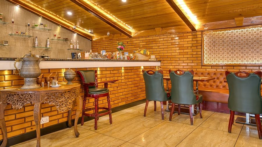 Bar counter with brick walls and high chairs at Royal Comfort Regency, creating a chic and comfortable lounge vibe for guests.