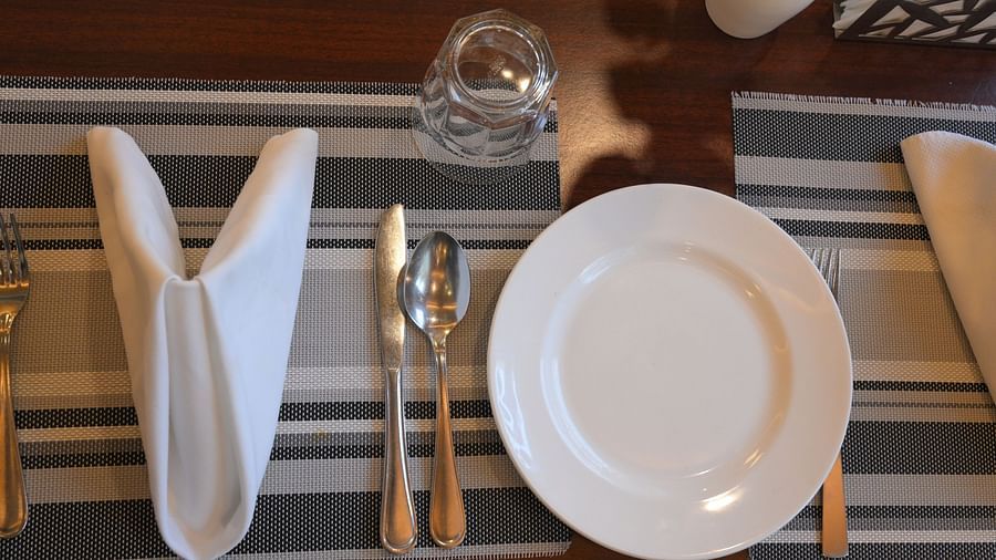 Neatly arranged dining table with striped runner and elegant place settings at Royal Comfort Regency ready to welcome guests.