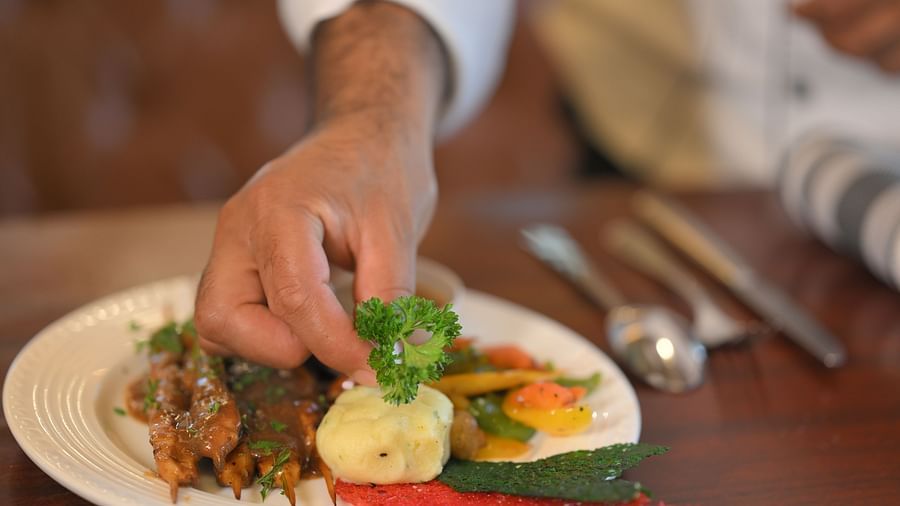 Chef plating a gourmet dish with artistic precision at Royal Comfort Regency, blending flavour and presentation effortlessly.