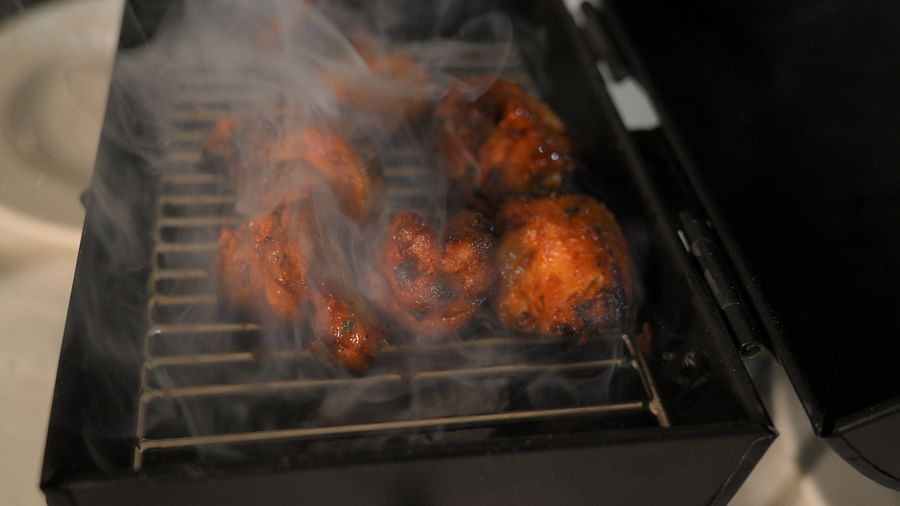 Tandoori delights sizzling on a smoky grill at Royal Comfort Regency showcasing authentic live cooking at its best.